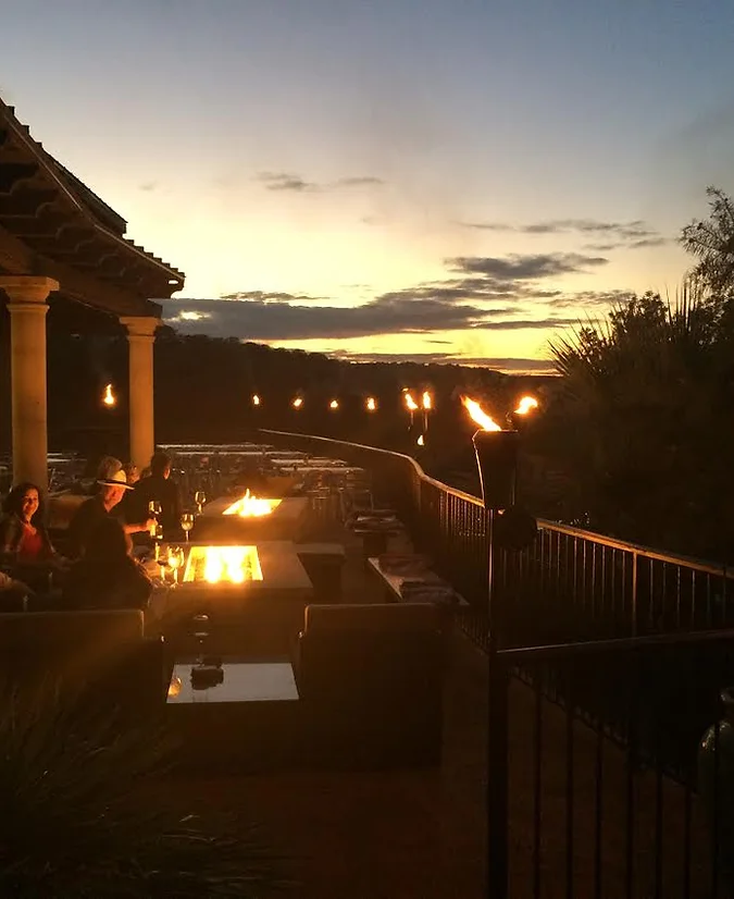 Couple eating on the deck of a restaurant at sunset with fire lit