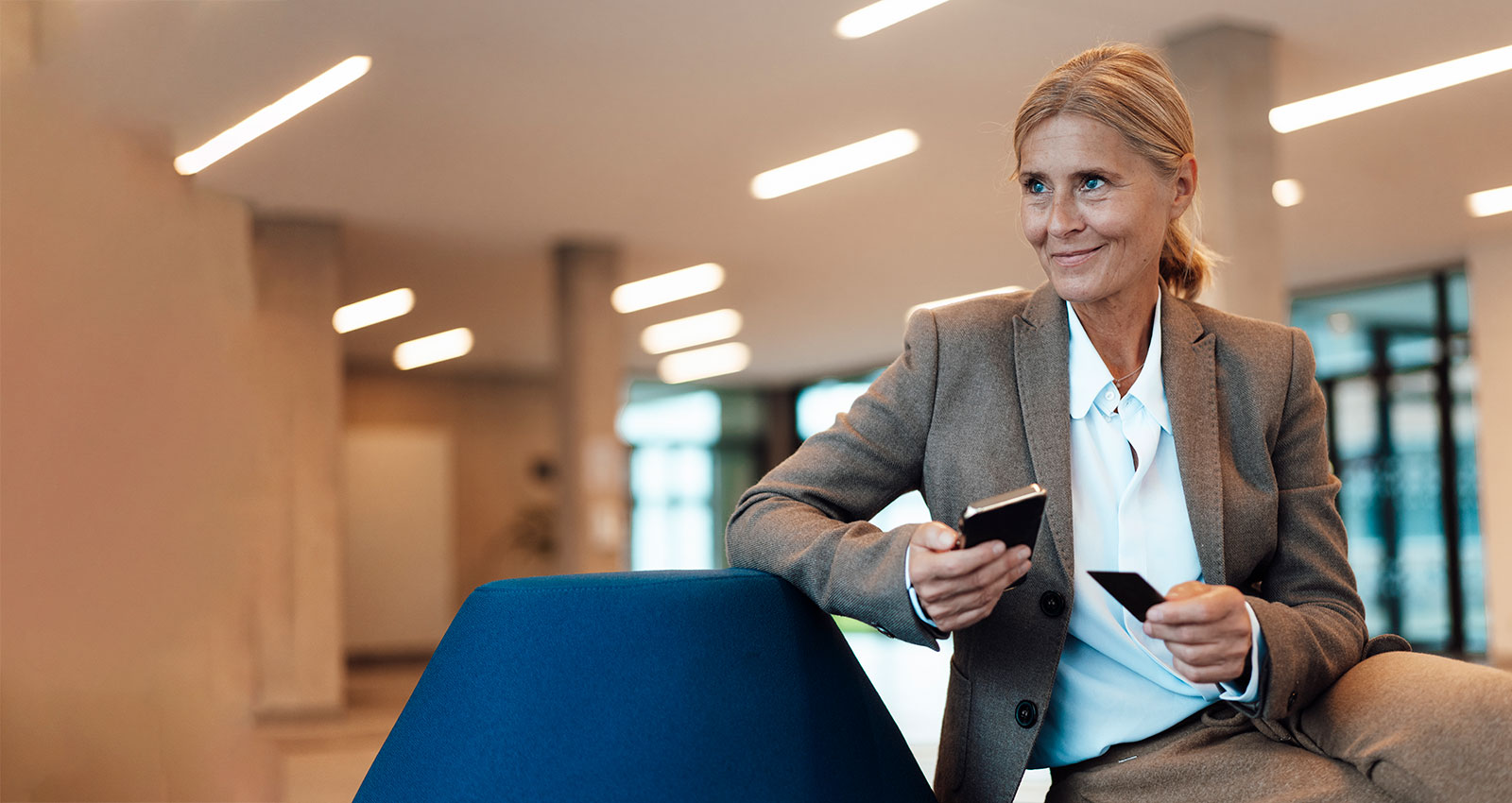 Middle aged blonde woman dresses in a suite holding her phone