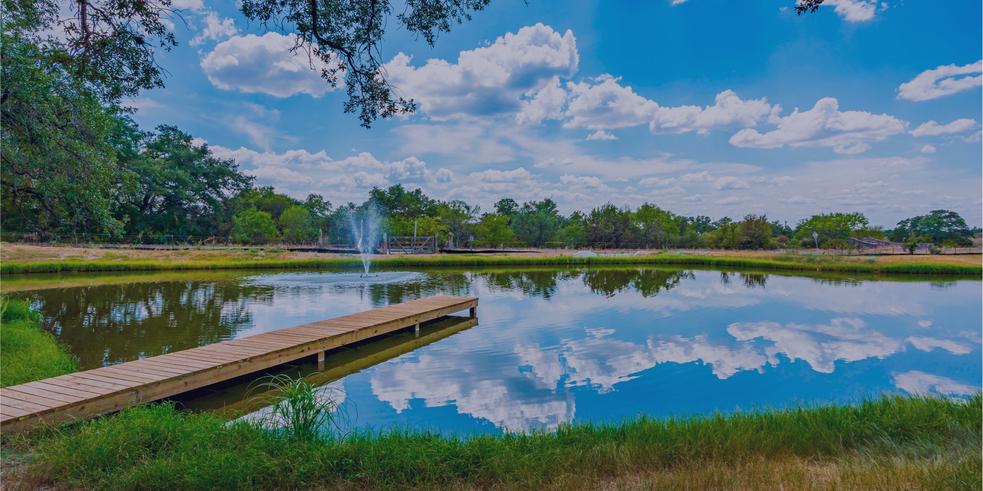 Dock on a pond with the reflection of clouds in the water