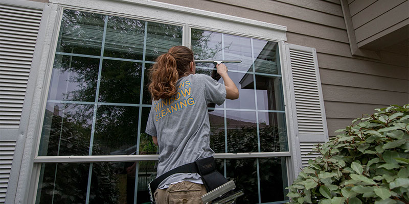 Person professionally cleaning windows on home exterior